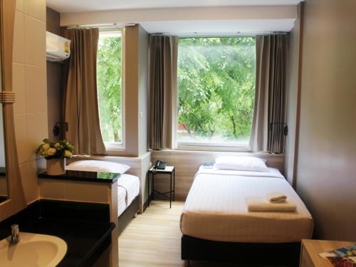 a hotel room with two beds and a sink and a window at YWCA Hotel Bangkok in Bangkok