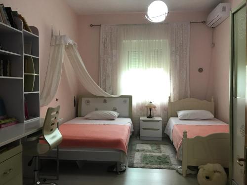 two beds in a room with pink walls and a window at Guesthouse Hygge in Tirana