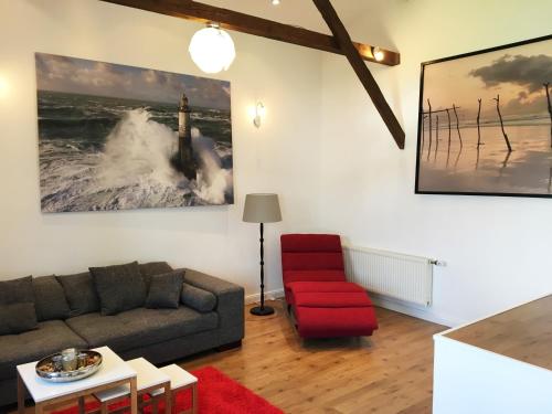 sala de estar con sofá y silla roja en Seadrift Land-Apartments, en Sankt Peter-Ording