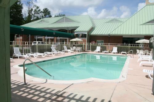 a large swimming pool with chairs and tables and a building at Days Inn by Wyndham Petersburg/South Fort Lee in Petersburg