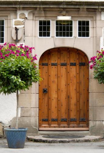 a wooden door on the side of a building with flowers at Losehill House Hotel & Spa in Hope