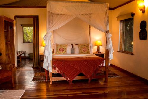 ein Schlafzimmer mit einem Himmelbett in einem Zimmer in der Unterkunft Ziwa Bush Lodge in Nakuru