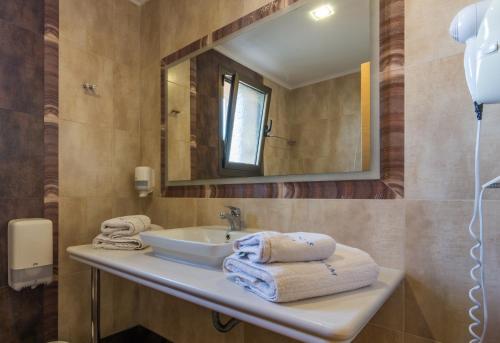 a bathroom with a sink and a mirror and towels at Aegean Dream Hotel in Karfas