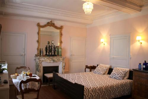 Schlafzimmer mit einem Bett, einem Tisch und einem Spiegel in der Unterkunft Chambres d'hôtes La Distillerie B&B in Saint-Germain-du-Bois