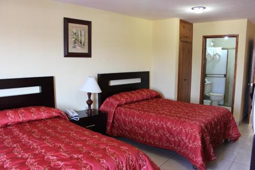 a hotel room with two beds and a bathroom at Hotel Conquistadores in Zacatecas