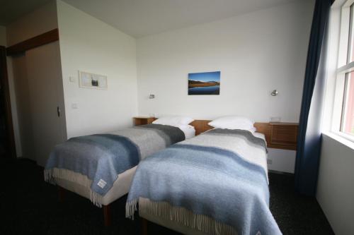 two beds in a room with blue and white blankets at Brunnholl Country Guesthouse in Höfn