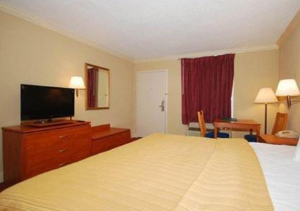a hotel room with a bed and a flat screen tv at Greenville Inn & Suites in Greenville