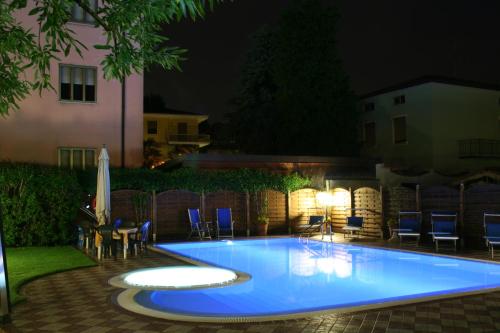 a swimming pool at night with chairs and a table at Albergo Al Cacciatore in Desenzano del Garda