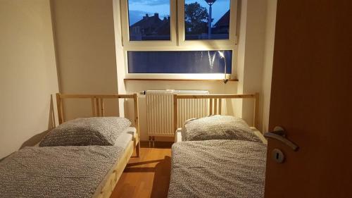 two beds in a room with a window at Gästehaus Samuel in Völklingen