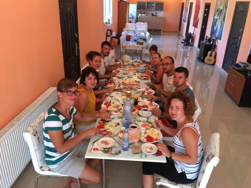 a group of people sitting at a table eating food at Hostel Denisa in Buzau