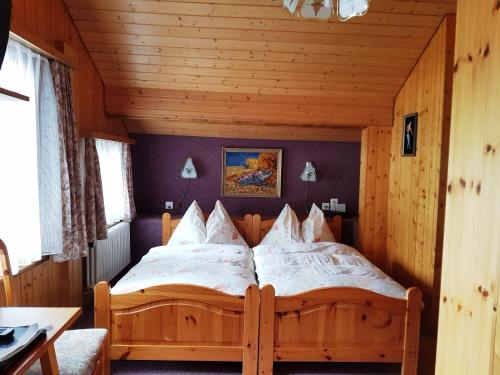 ein Schlafzimmer mit einem Holzbett in einem Zimmer in der Unterkunft Alpine Budget Rooms by Täscherhof in Täsch
