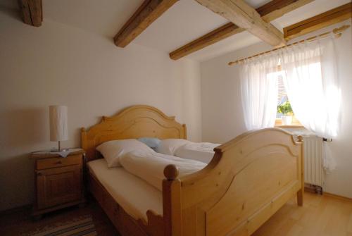 a bedroom with a wooden bed and a window at Gasthaus Fischerrosl in Münsing am Starnberger See