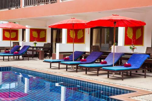 a pool with blue lounge chairs and red umbrellas at The Florist Resort in Mae Nam