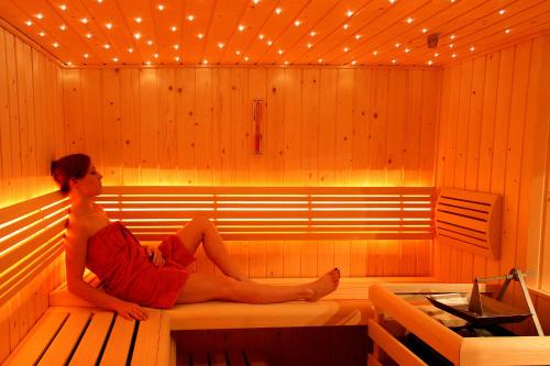 a woman sitting on a bench in a sauna at paNOORama appartementen in Noorbeek