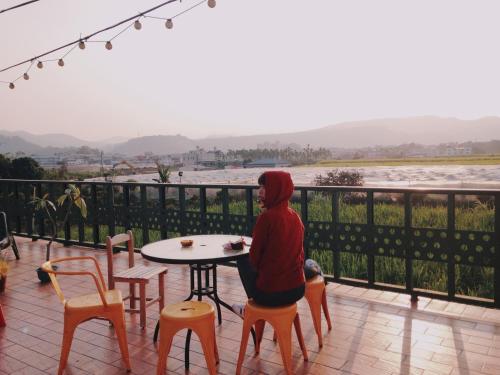 a woman sitting at a table on a balcony overlooking the water at Puli Islet Inn in Puli