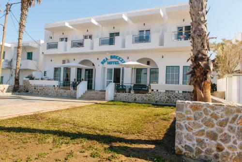a building with a palm tree in front of it at Sea Breeze Hotel in Mastichari