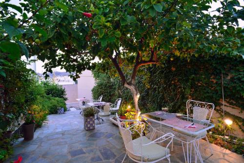 a patio with a table and chairs under a tree at 1901 Hermoupolis in Ermoupoli