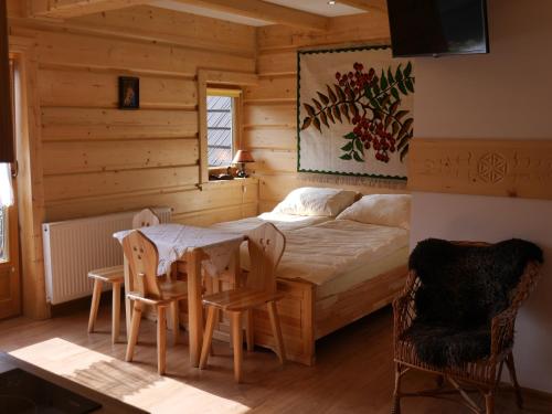 - une chambre avec un lit, une table et des chaises dans l'établissement Biołe Izby, à Chochołów