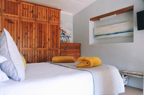 a bedroom with a bed with yellow towels on it at House Forget Me Not in Bredasdorp