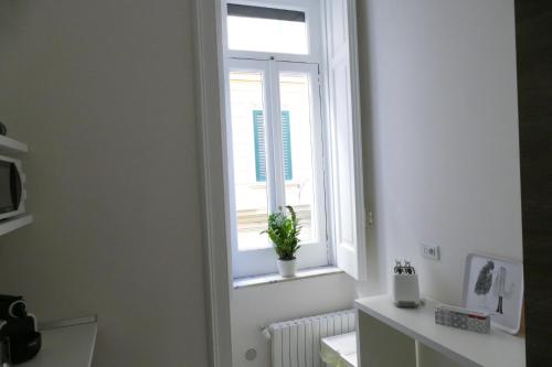 a bathroom with a window with a potted plant on the window sill at Luxury Manfredi Apartment Salerno in Salerno