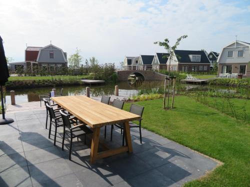 a wooden table and chairs on a patio with a pond at Luxurious Water Villa in Uitdam