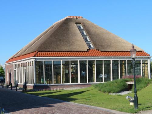 a building with a thatched roof with a lot of windows at Luxurious Water Villa in Uitdam