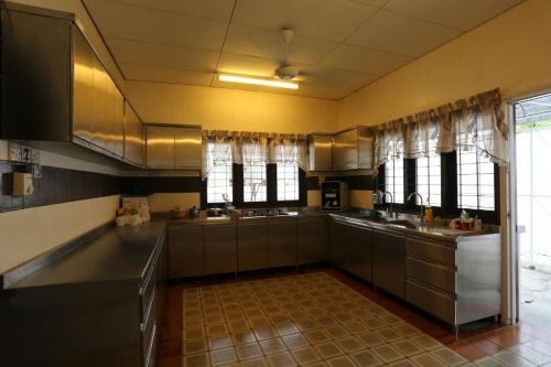 a large kitchen with stainless steel cabinets and windows at Bee's Homestay in George Town