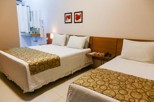 a hotel room with two beds and a table at Hotel Porto Madeira in Porto Velho