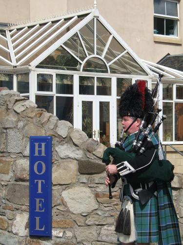 a man in a kilt standing next to a sign at Horizon Hotel in Ayr