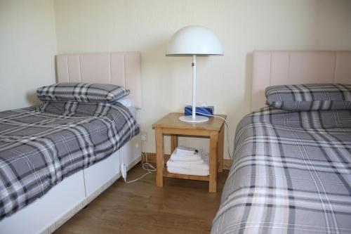 a bedroom with two beds and a table with a lamp at Inver bay apartment in Tain