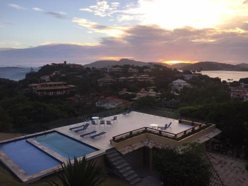 a swimming pool on top of a house with the sunset at Praia da Ferradurinha Guest House in Búzios