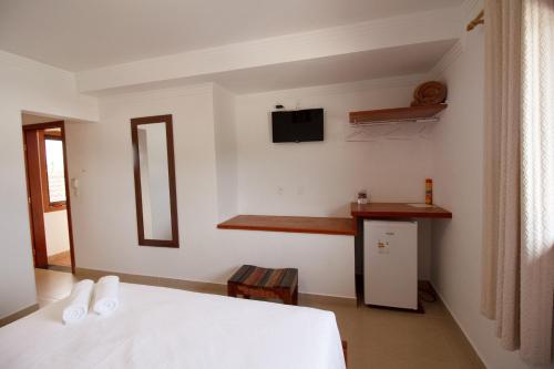 a bedroom with a bed and a tv on the wall at Pousada Acqua Azul in Bertioga