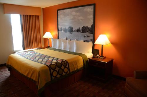 a hotel room with a bed with a painting on the wall at Super 8 by Wyndham Louisville/Expo Center in Louisville