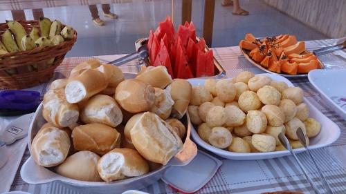 a table with plates of bread and vegetables on it at Pousada Santana - Trindade Goiás in Trindade
