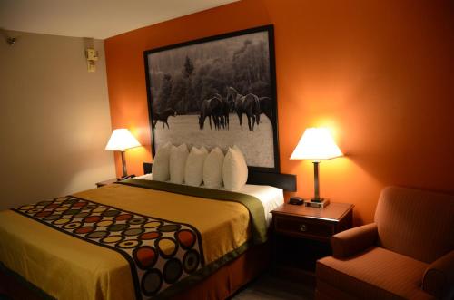 a hotel room with a bed with a painting on the wall at Super 8 by Wyndham Louisville/Expo Center in Louisville