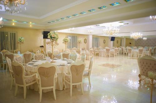 a banquet hall with white tables and chairs and chandeliers at Hotel Elita in Odesa