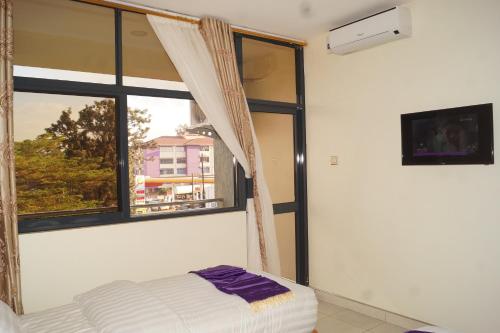 a bedroom with a bed and a window at Hotel OK Kampala in Kampala