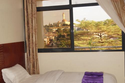 a bedroom with a window with a view of a city at Hotel OK Kampala in Kampala