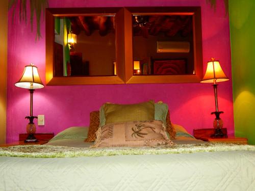 a bedroom with a bed with a pink wall and two lamps at Hotel Torres Del Fuerte in El Fuerte