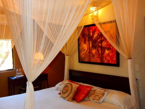 a bedroom with a bed with white curtains and red pillows at Hotel Torres Del Fuerte in El Fuerte