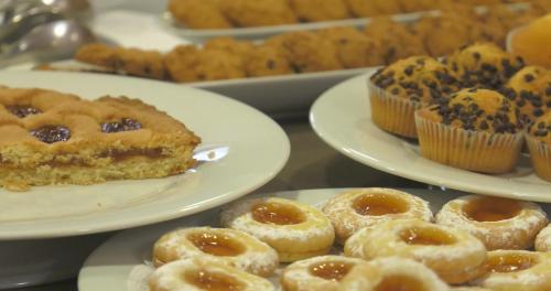 a table topped with plates of donuts and pastries at Hotel Centro Benessere Gardel in Arta Terme