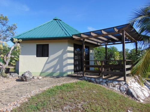 un petit bâtiment blanc avec un toit vert dans l'établissement Gumbo Limbo Jungle Resort, à Cool Shade