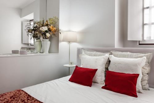 een slaapkamer met een wit bed met rode kussens bij Casa Becco dos Assucares, com free garagem - Centro Histórico in Évora