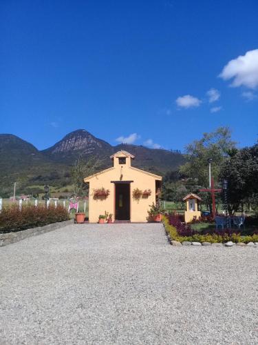 a small white church with mountains in the background at Hotel Campestre Franchesca in Tabio
