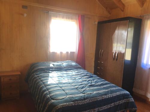 a bedroom with a bed and a dresser and a window at Cabañas Los Canelos Pucon, Hermosa Granja de 20 hectaréas a orillas del Río Liucura in Pucón