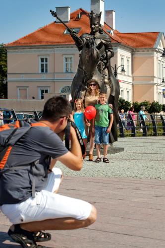 a man taking a picture of a little boy in front of a statue at Hotel Centrum Malbork in Malbork