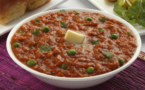a bowl of chili with peas and cheese on a table at Kuber's Residency in Mahad
