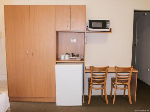 eine Küche mit einem weißen Kühlschrank und 2 Stühlen in der Unterkunft Motel Riverina in Leeton