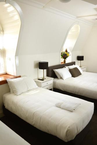 two beds in a room with two windows at Grand Hotel Healesville in Healesville