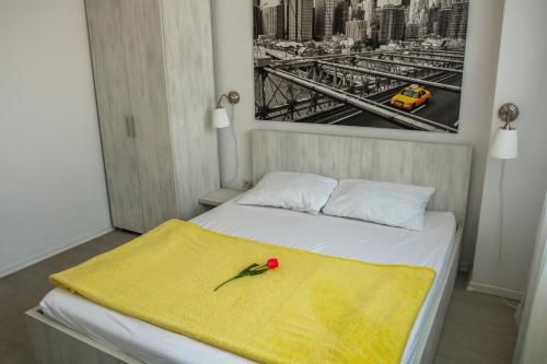 ママイア・ノルドにあるGreen 24 Apartmentの黄色の毛布と赤い花が付いたベッド